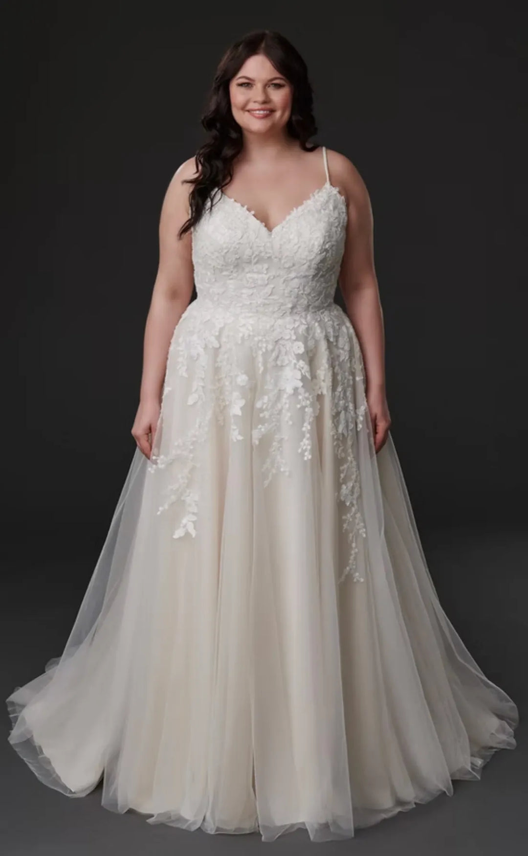 Woman wearing a white lace wedding dress against a dark background