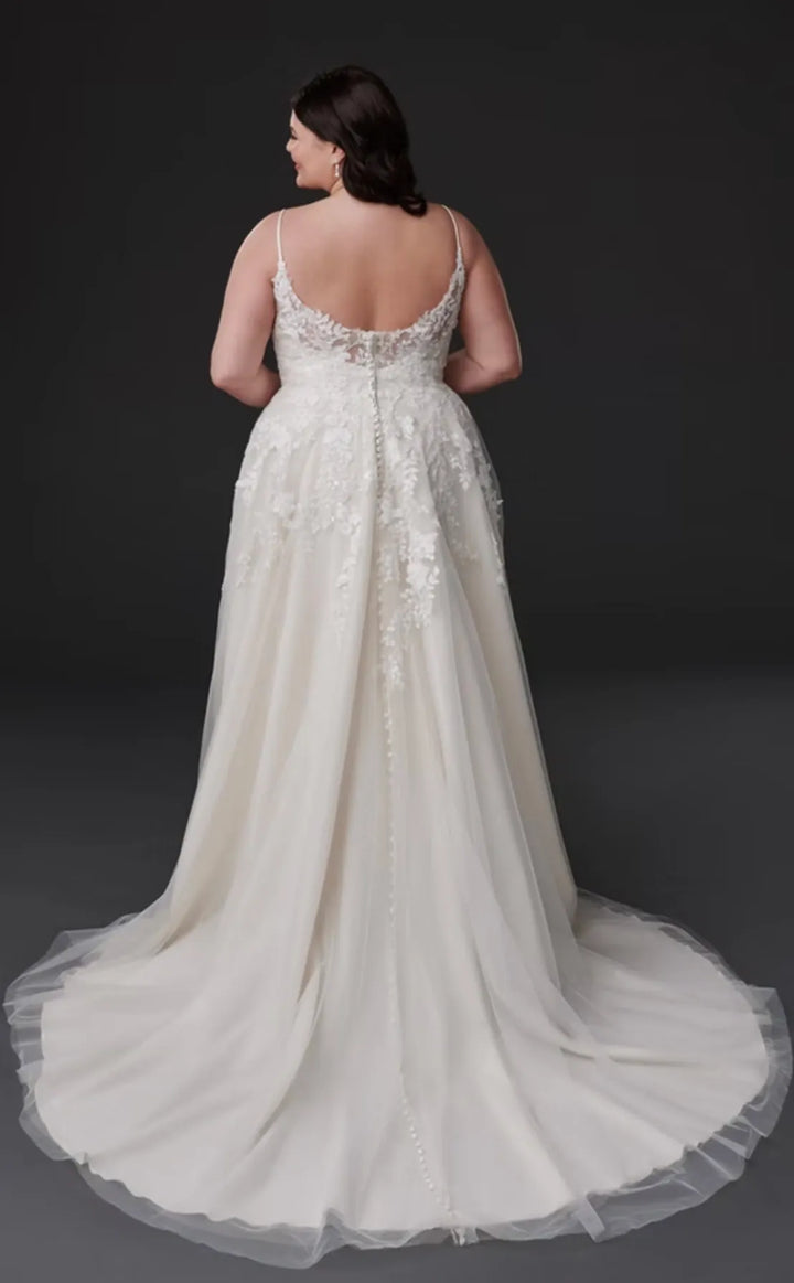 Woman wearing a white wedding dress with a sheer back on a dark background