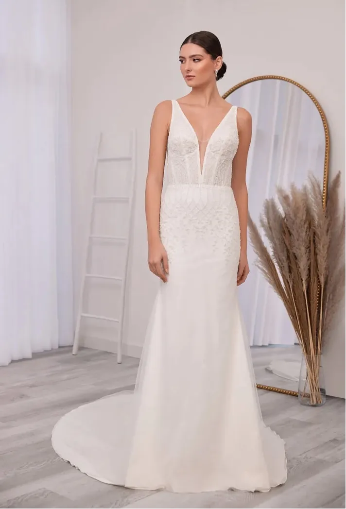 Woman wearing a white wedding dress in a minimalistic room with a ladder and decorative plant.