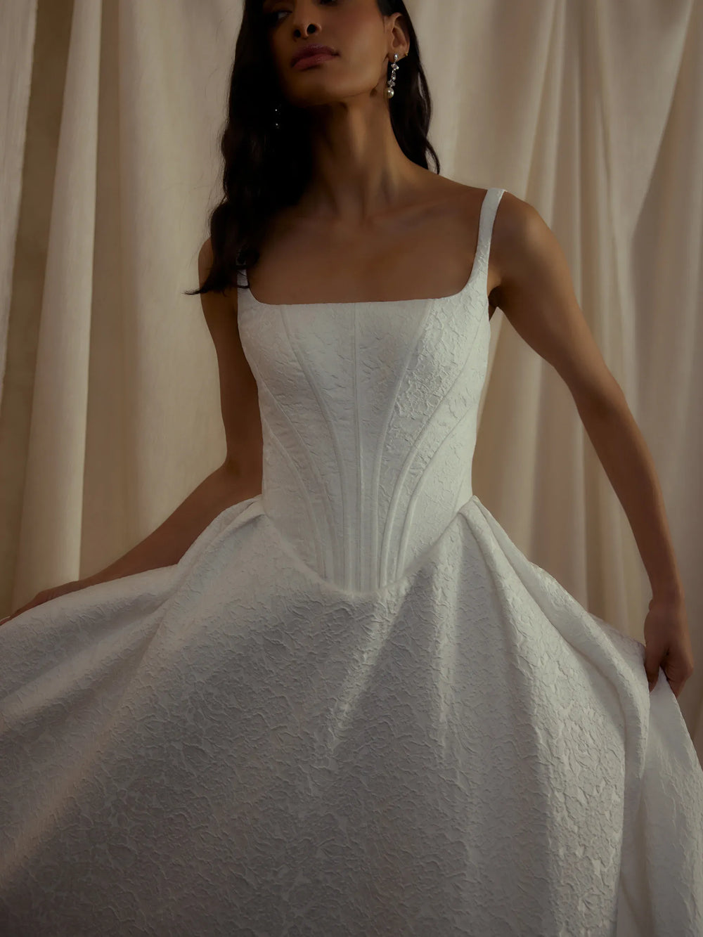 White wedding dress with intricate detailing on a neutral background