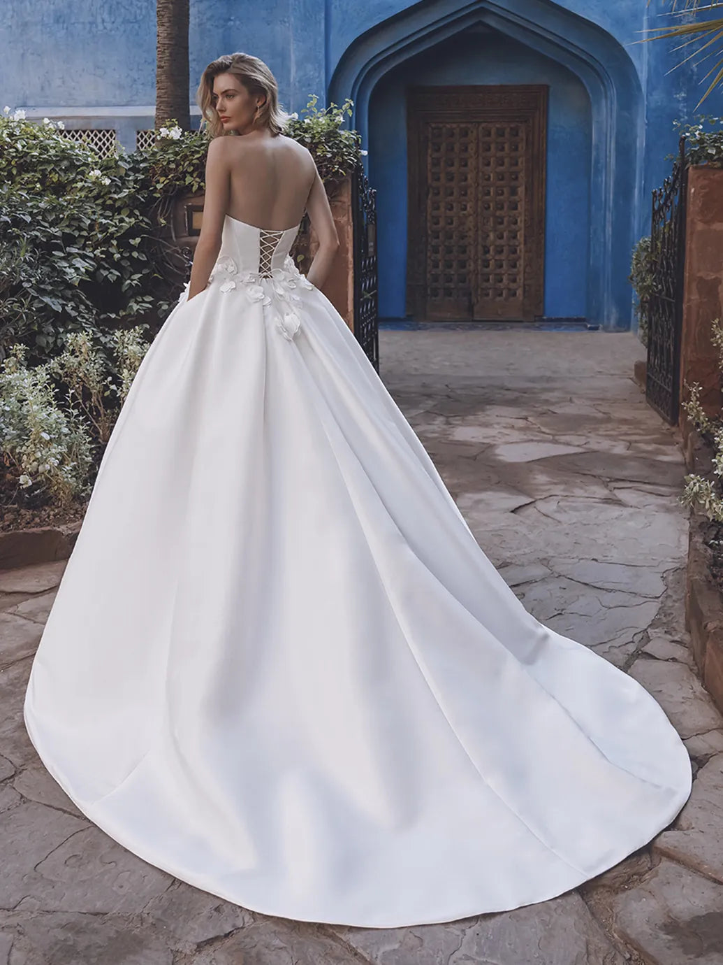 Woman in a white wedding dress standing in front of a blue archway.