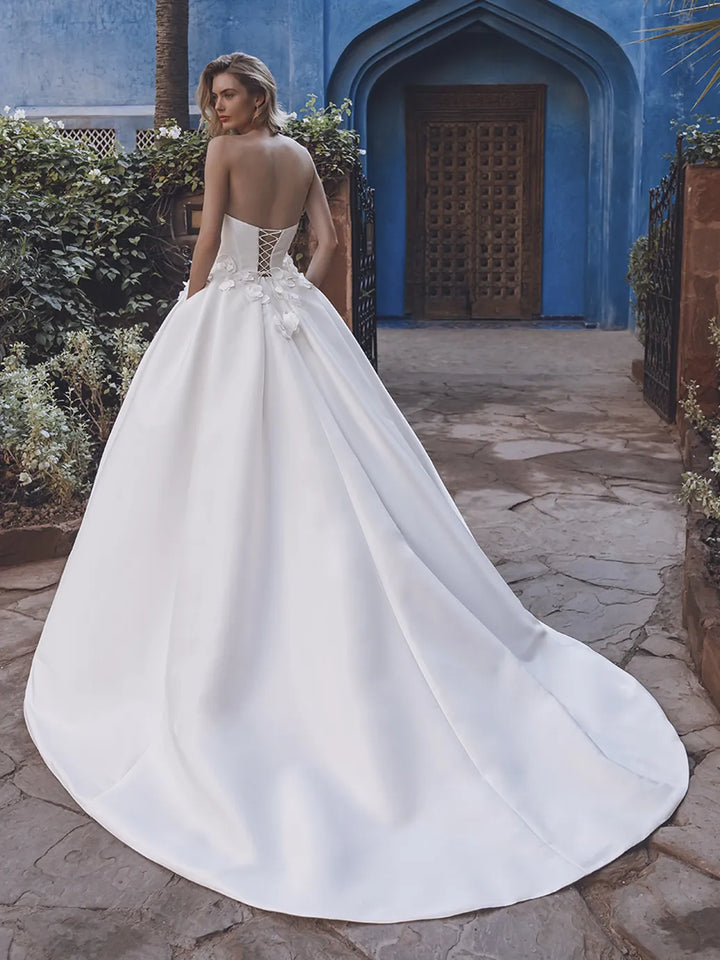 Woman in a white wedding dress standing in front of a blue archway.