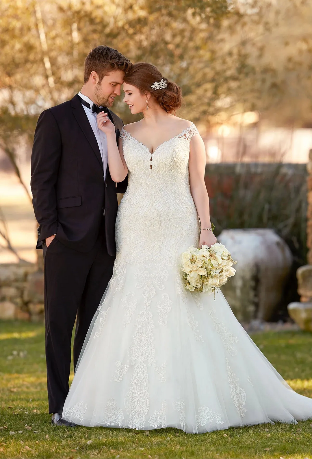 Couple in wedding attire standing outdoors with a blurred background