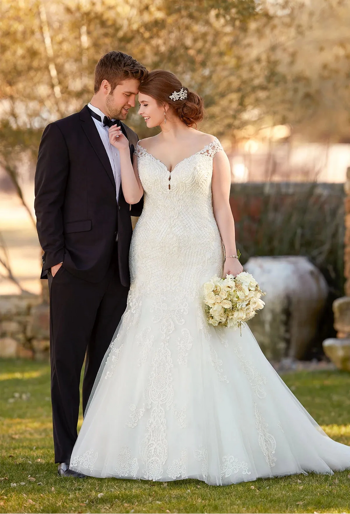 Couple in wedding attire standing outdoors with a blurred background