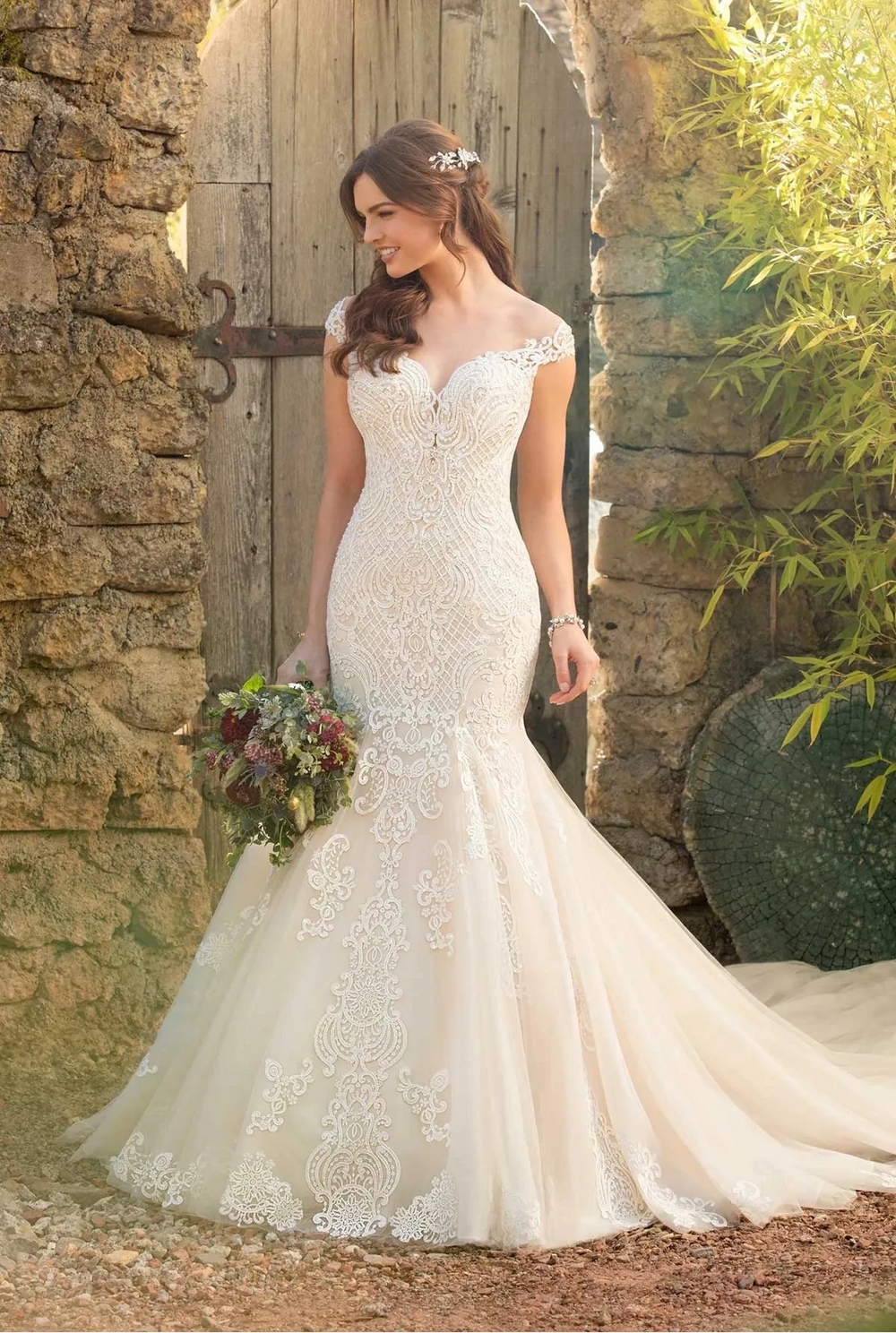 Woman in a wedding dress standing in front of a rustic wooden door.