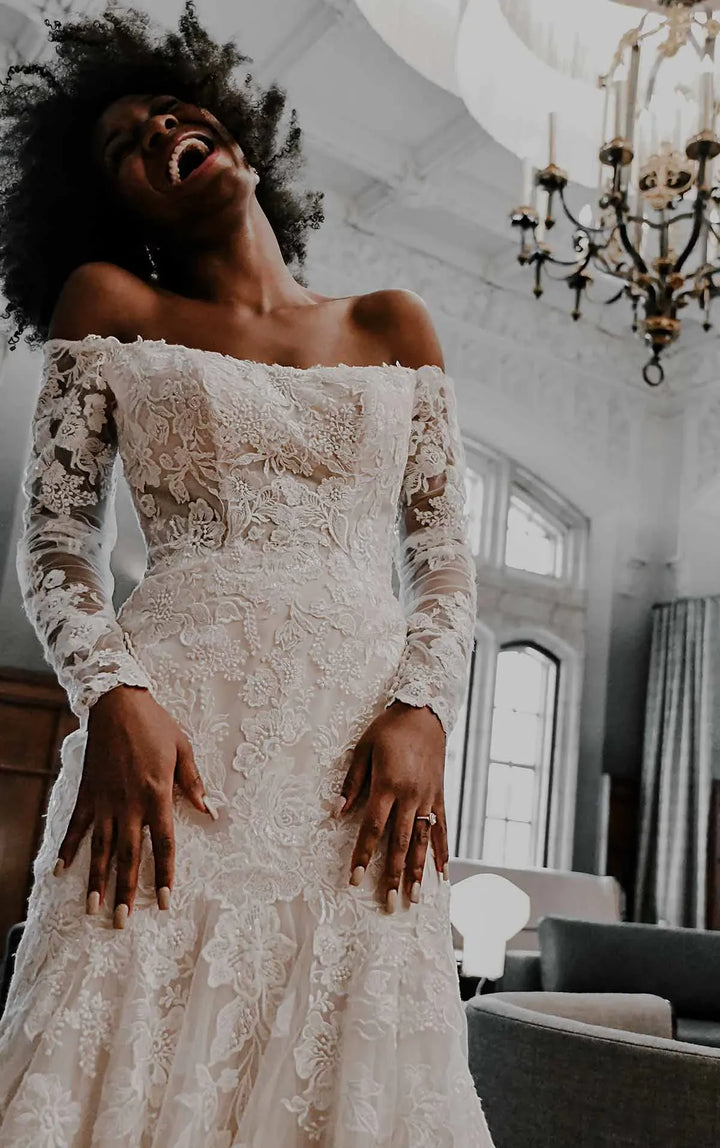 Woman in a lace wedding dress with long sleeves in an elegant room.