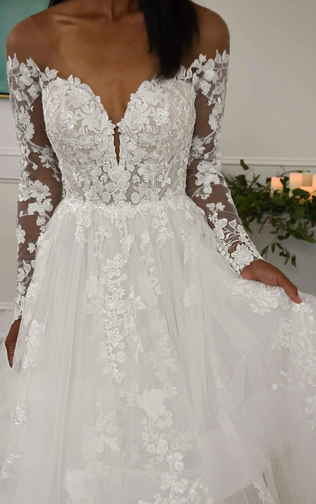 close up of front of essense of australia d3274 tulle ball gown wedding dress showing off the shoulder long sleeves neckline and lace appliques