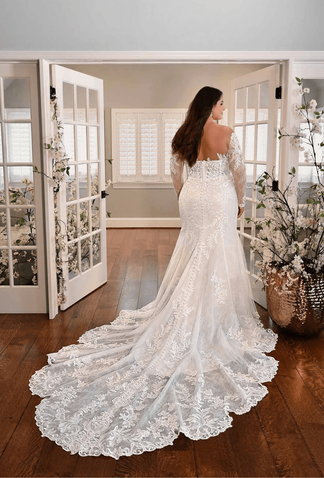 full back of essense of australia ivory lace fit and flare wedding dress featuring an off the shoulder neckline with long sleeves. and a long shaped train