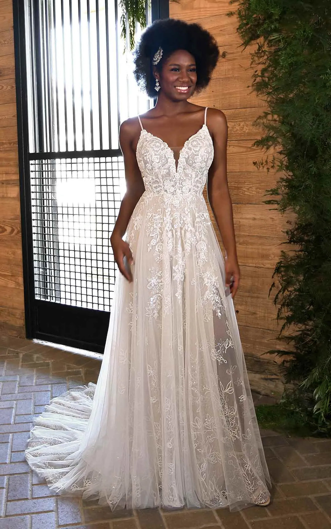 Woman wearing a white lace wedding dress standing outdoors.