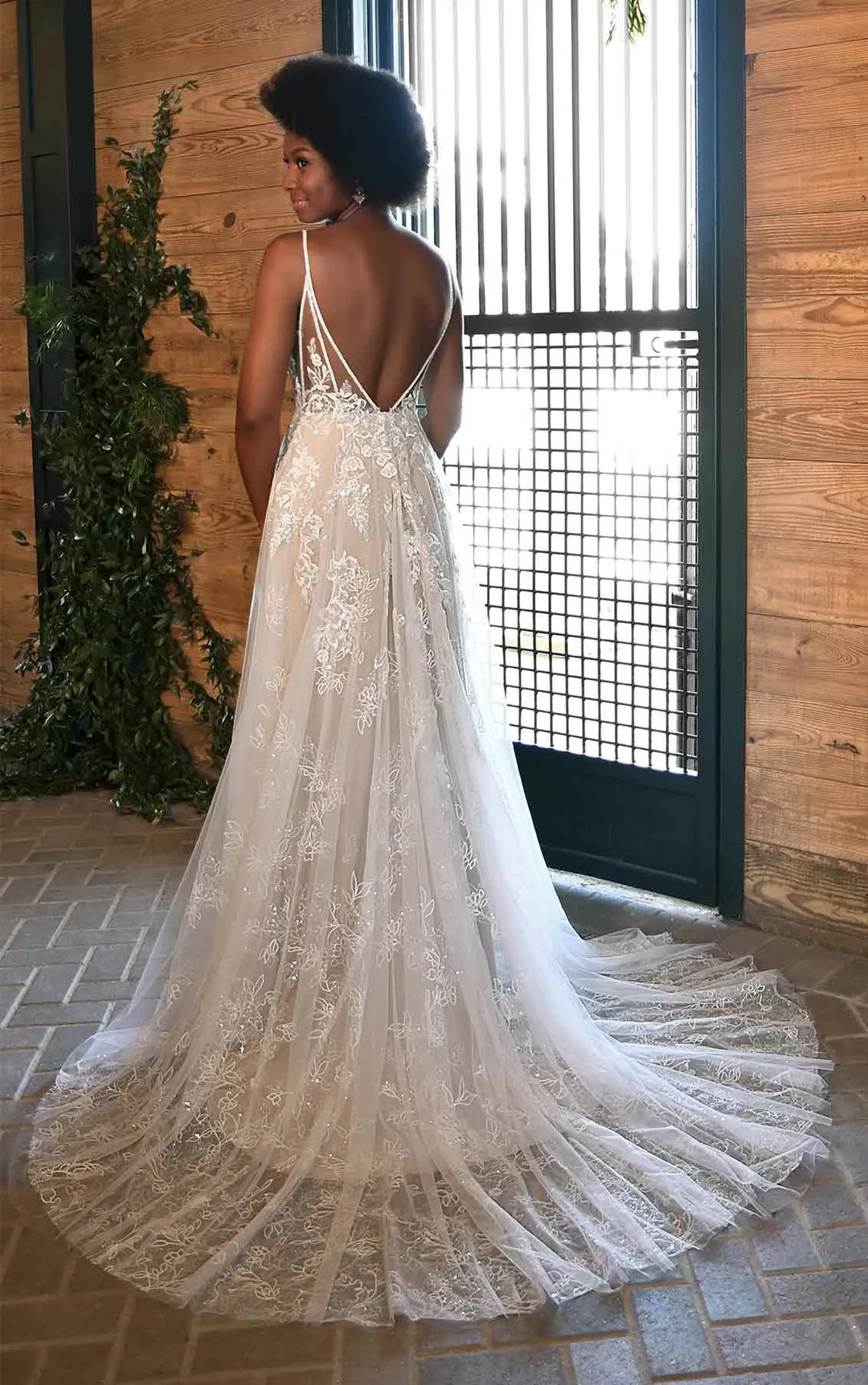 Woman wearing a white lace dress standing in front of a wooden wall.