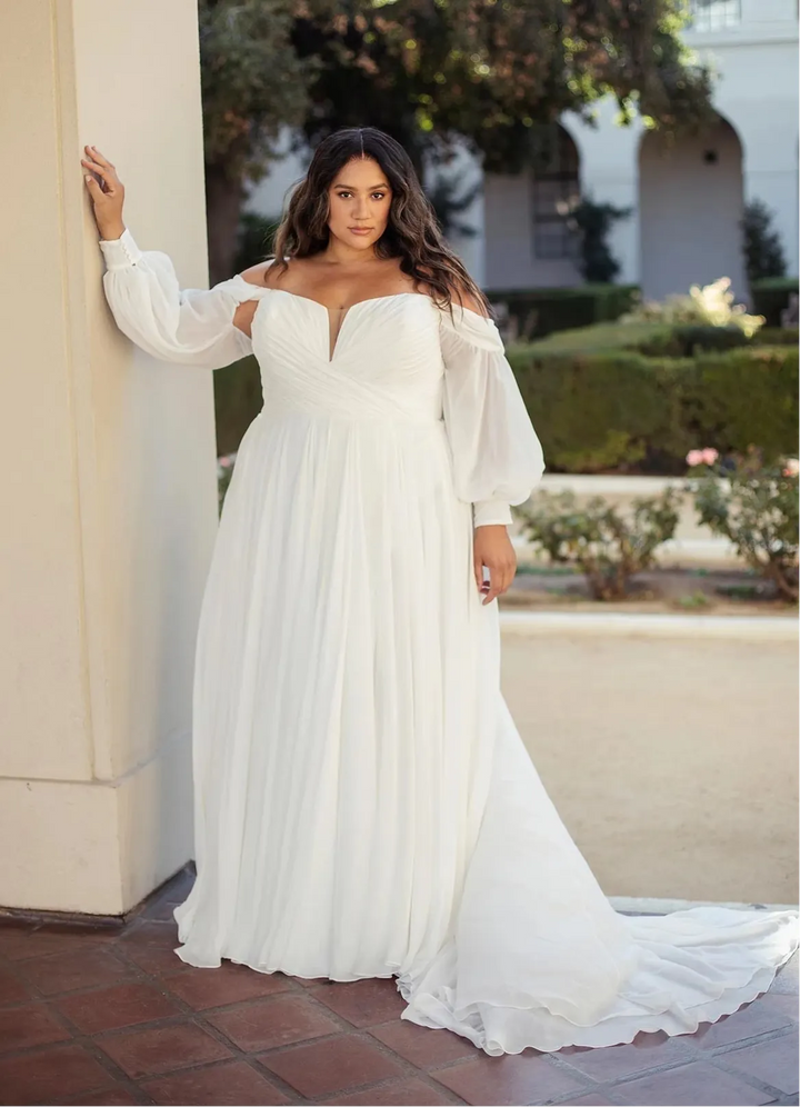 Woman in a white wedding dress standing outdoors near a building.