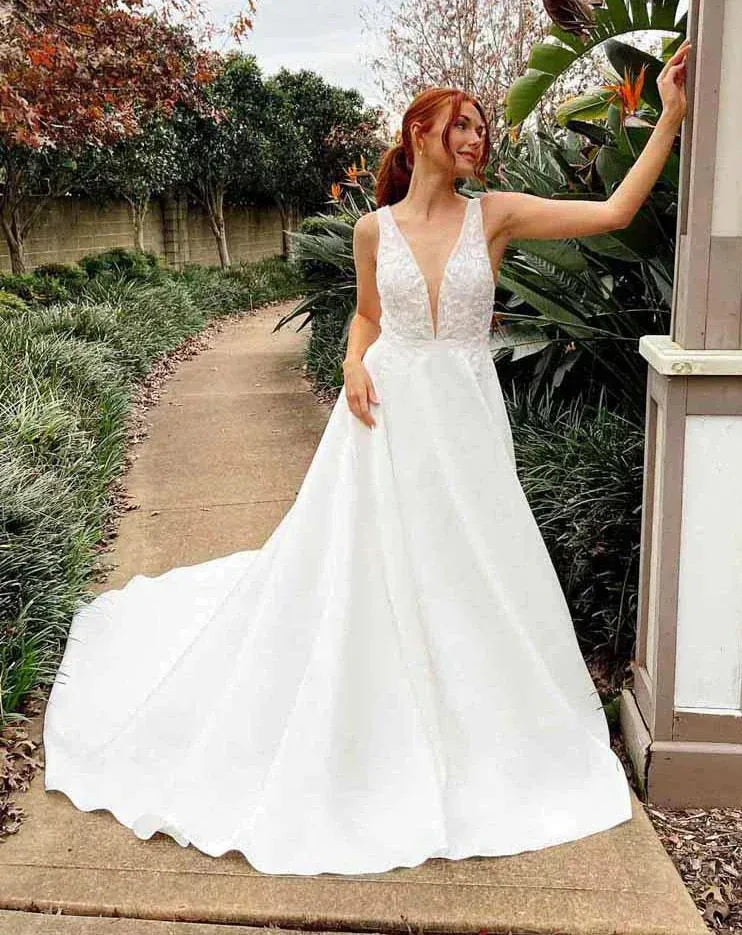 Woman in a white wedding dress standing outdoors with greenery around