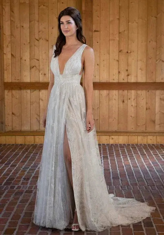 Woman wearing a white lace dress with a deep neckline and slit in a rustic setting.