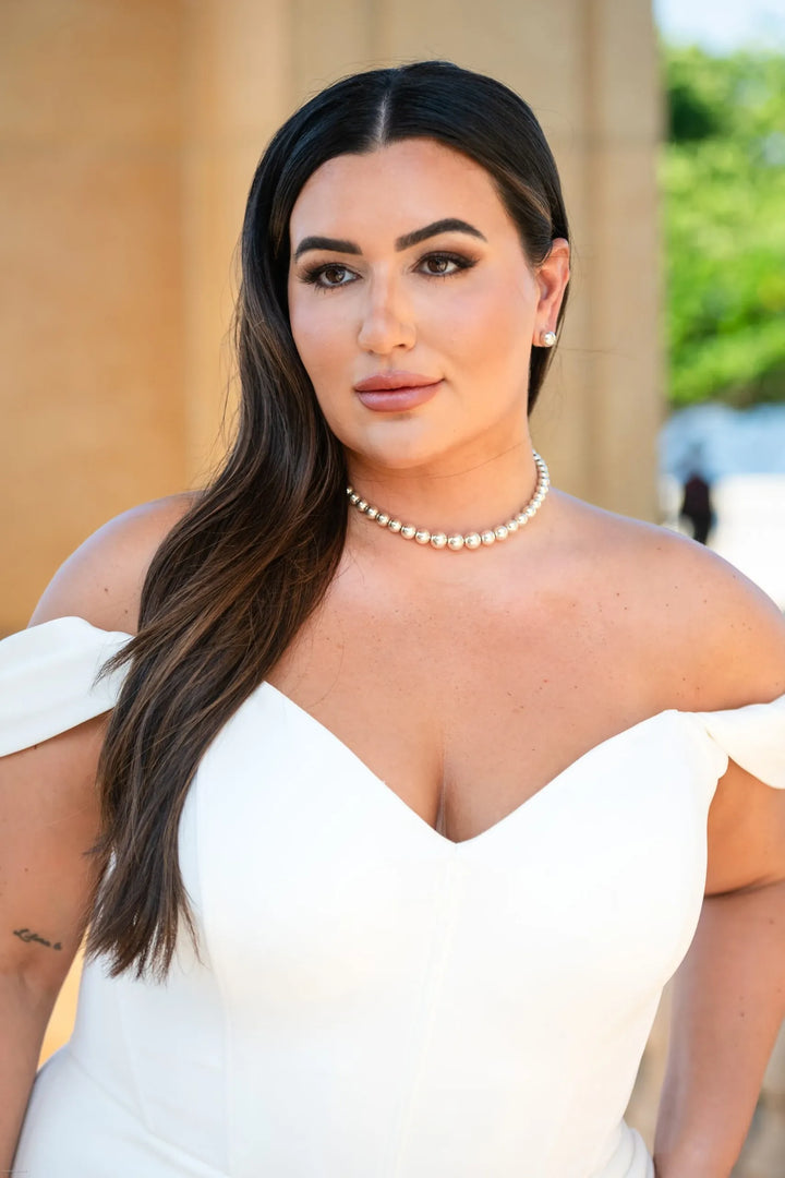 close up of essense d3864 ivory crepe fitted wedding dress featuring an off the shoulder neckline 