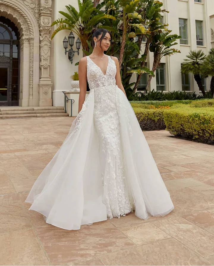 Woman in a white wedding dress standing in front of a historic building with palm trees.