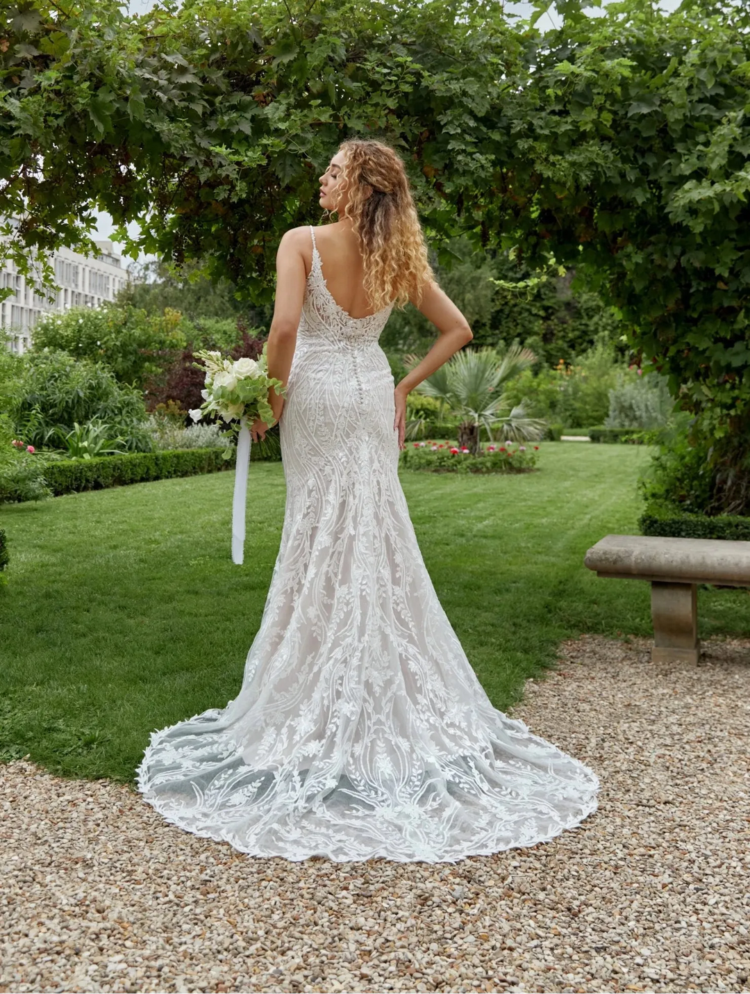 Woman in a white lace wedding dress standing in a garden