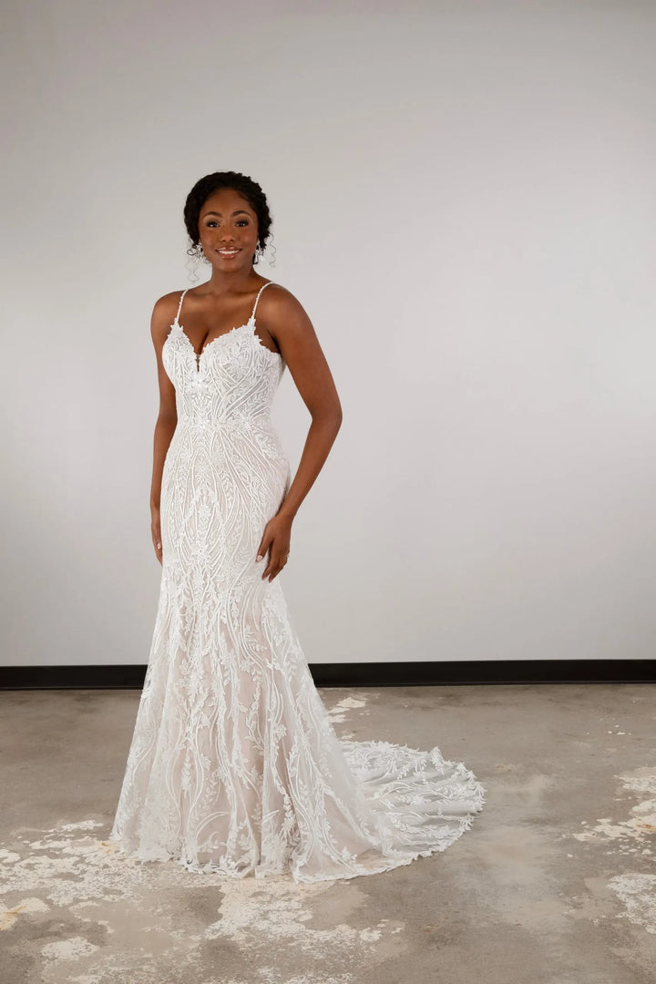 Woman wearing a white lace wedding dress against a plain background