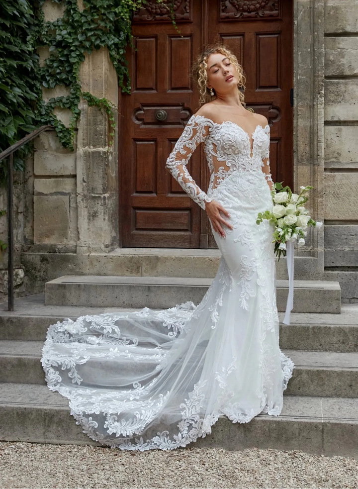 Woman in a white wedding dress standing on steps with ivy-covered walls in the background