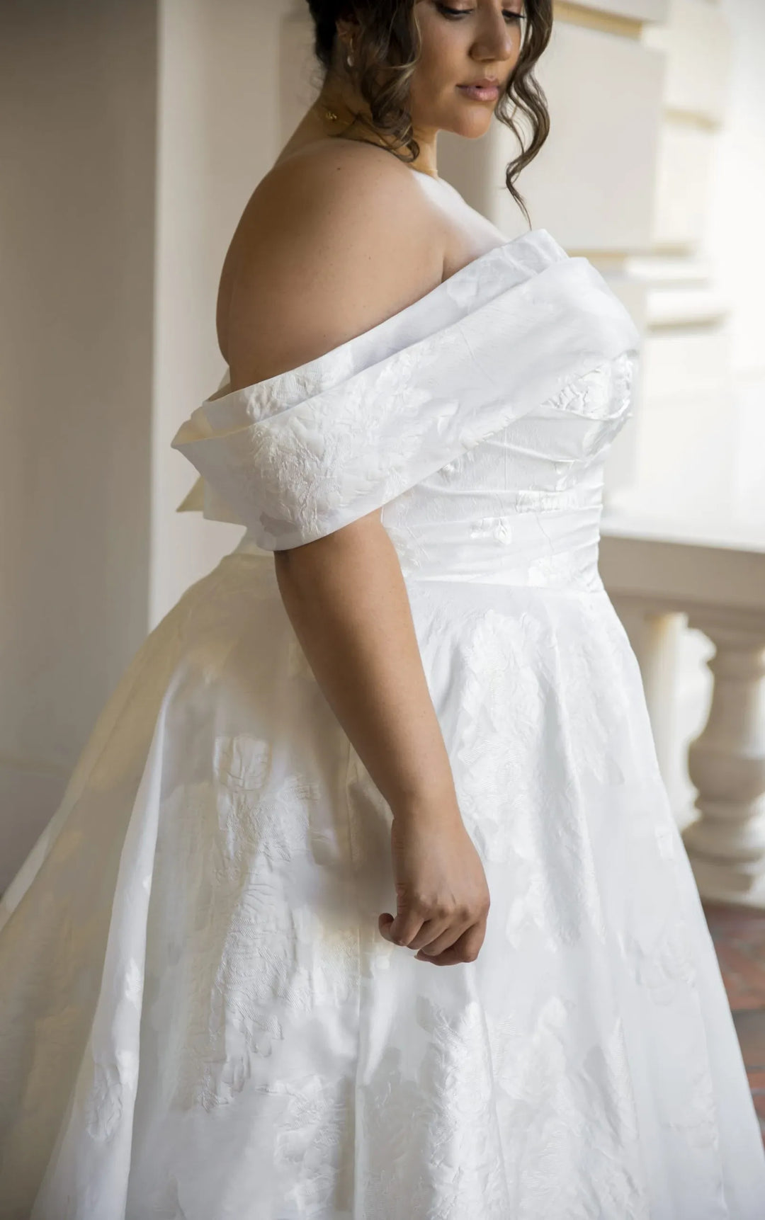 Woman wearing a white off-shoulder dress in an indoor setting