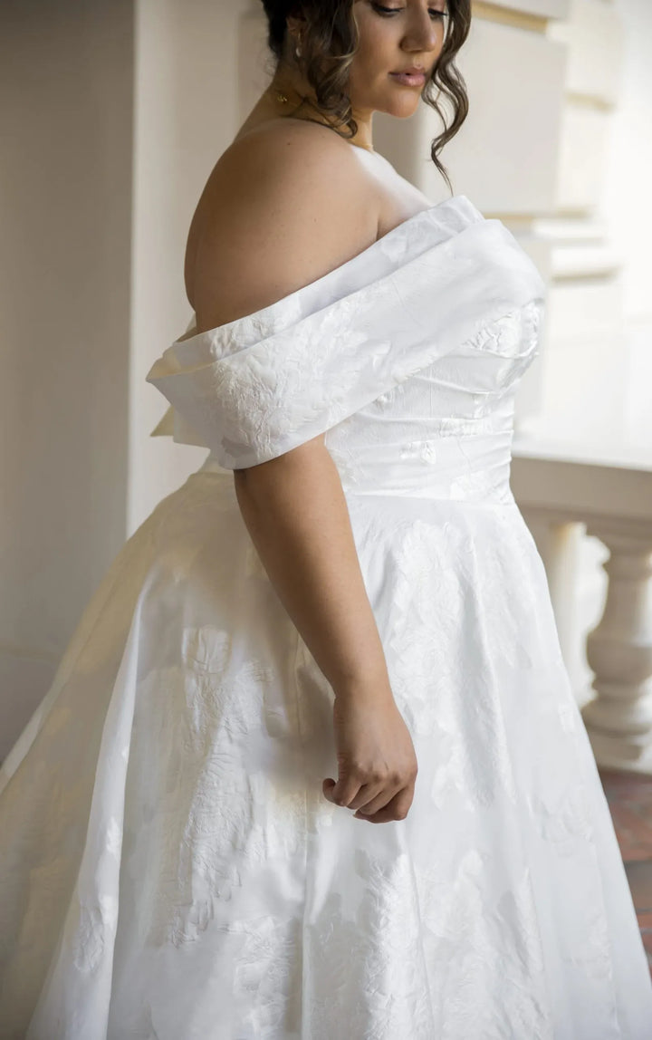 Woman wearing a white off-shoulder dress in an indoor setting