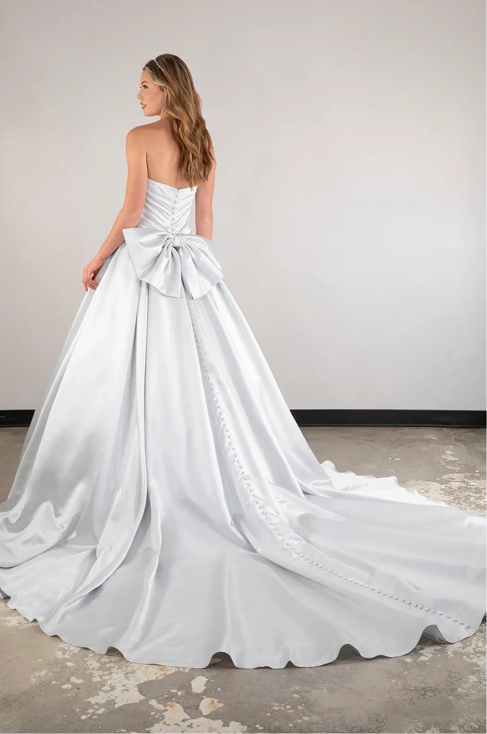 White wedding dress with a large bow detail on a plain background