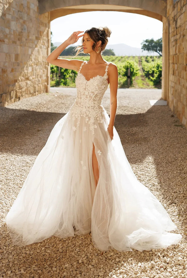 Woman in a white wedding dress standing in a rustic outdoor setting.