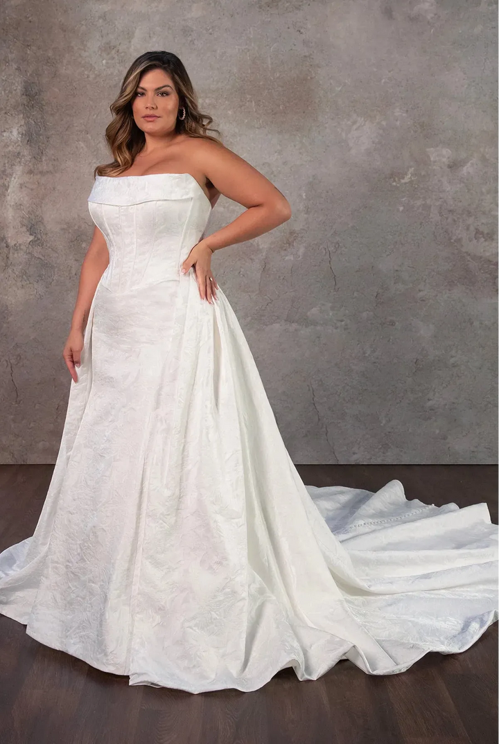 Woman wearing a white strapless gown against a neutral background