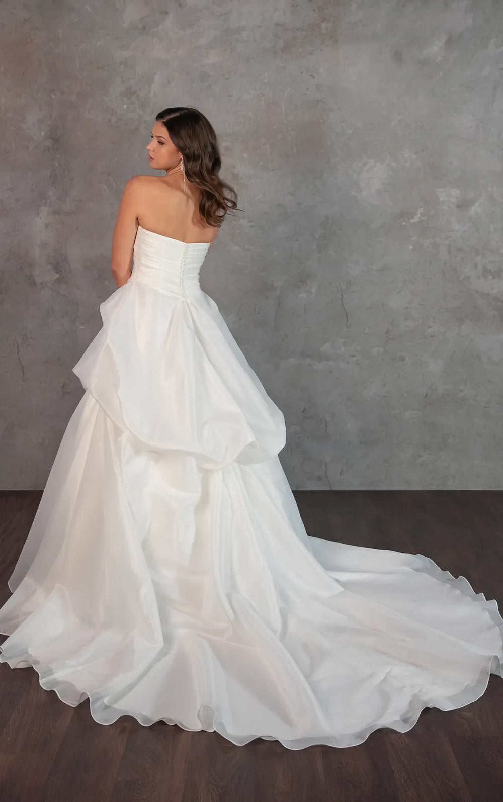 Woman wearing a white strapless wedding dress against a gray background