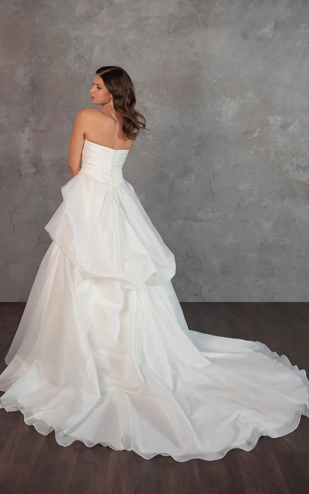 Woman wearing a white strapless wedding dress against a gray background
