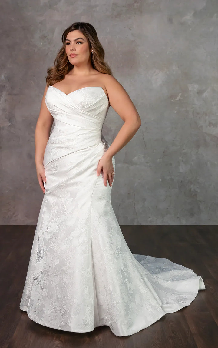 Woman wearing a white strapless wedding dress against a gray background