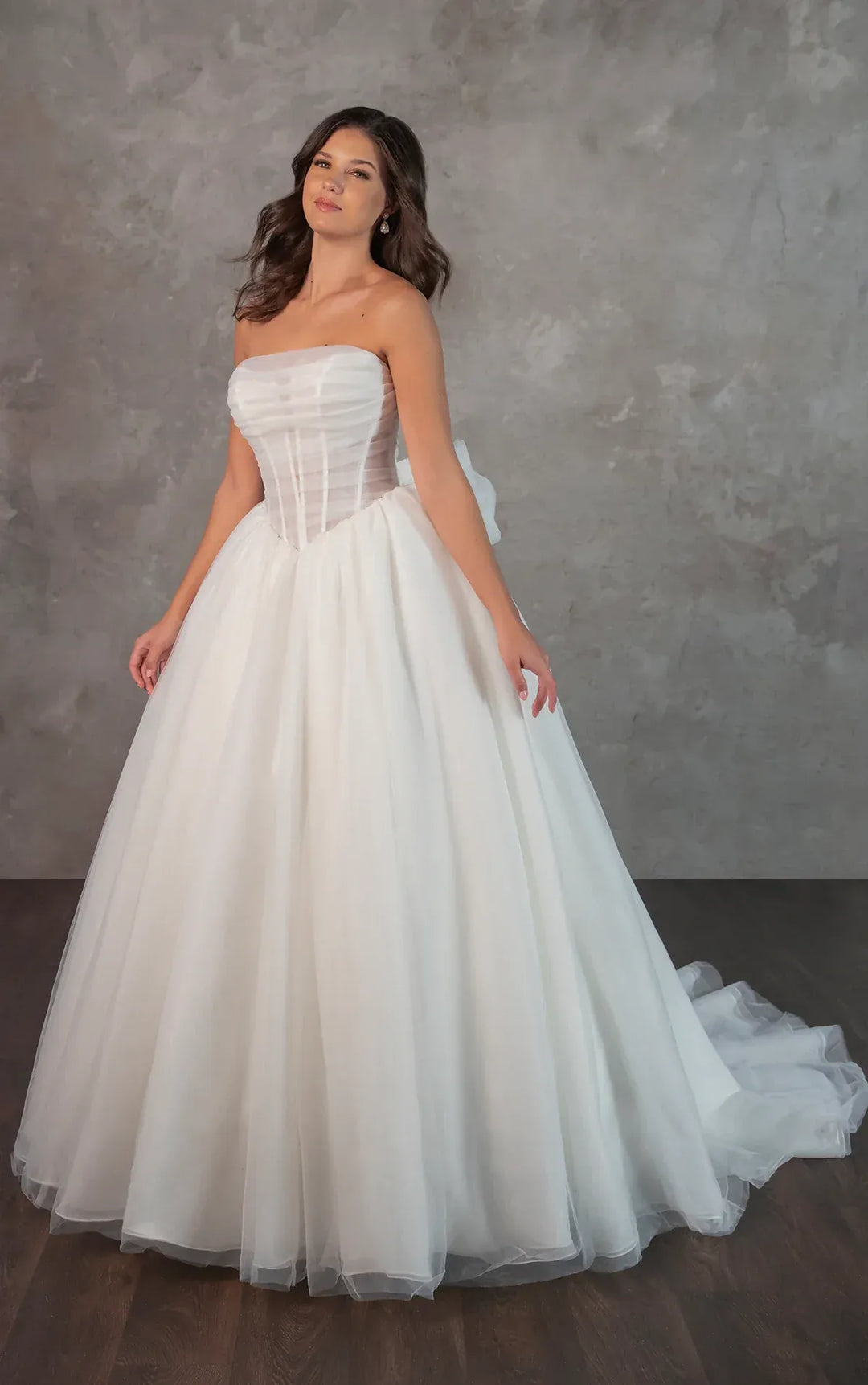 Woman wearing a strapless white wedding dress against a gray background