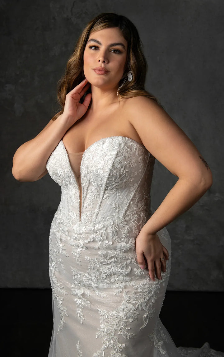 Woman wearing a strapless lace wedding dress against a dark background