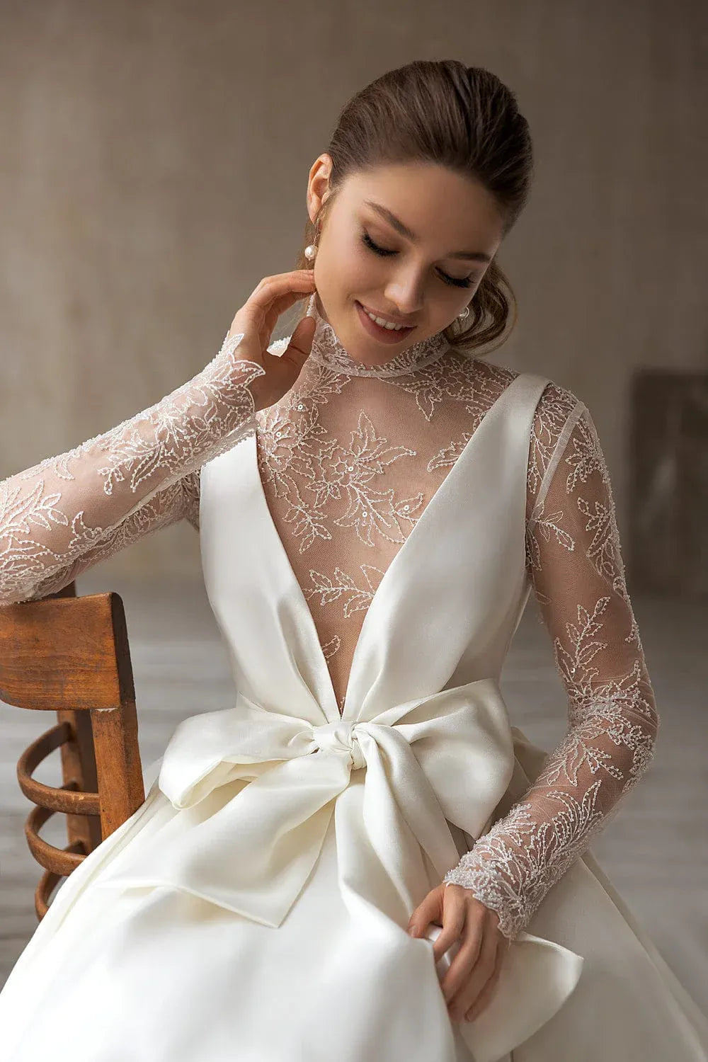 close up of eva lendel magdalena ivory mikado a-line wedding dress with a bow on the bodice and a matching lace long sleeve bodice