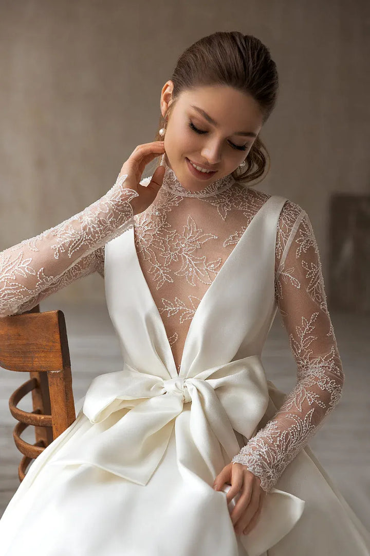 close up of eva lendel magdalena ivory mikado a-line wedding dress with a bow on the bodice and a matching lace long sleeve bodice