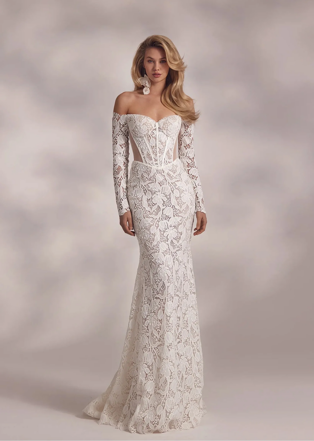 Woman wearing a white lace wedding dress against a neutral background