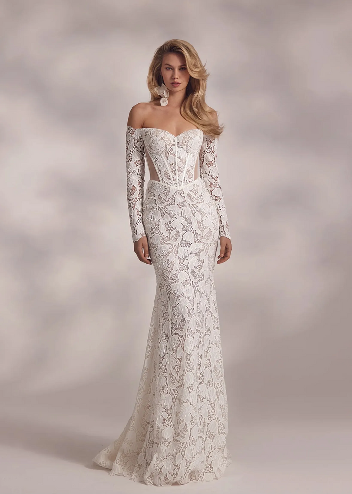Woman wearing a white lace wedding dress against a neutral background