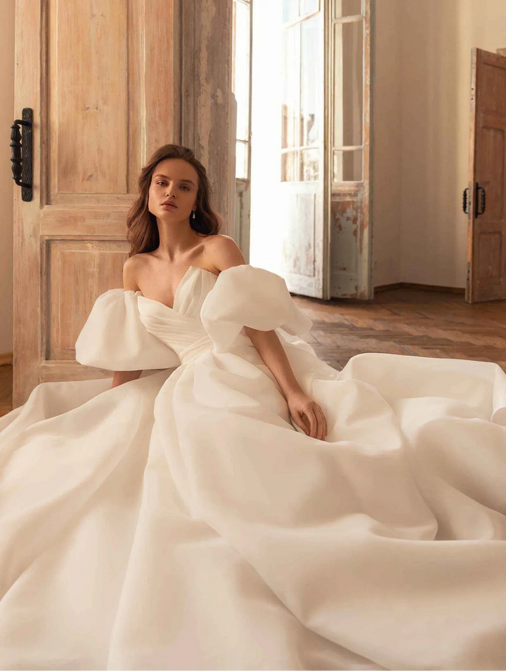 close up of eva lendel samanta ivory organza a-line wedding dress with a strapless v neckline and detached cap sleeves