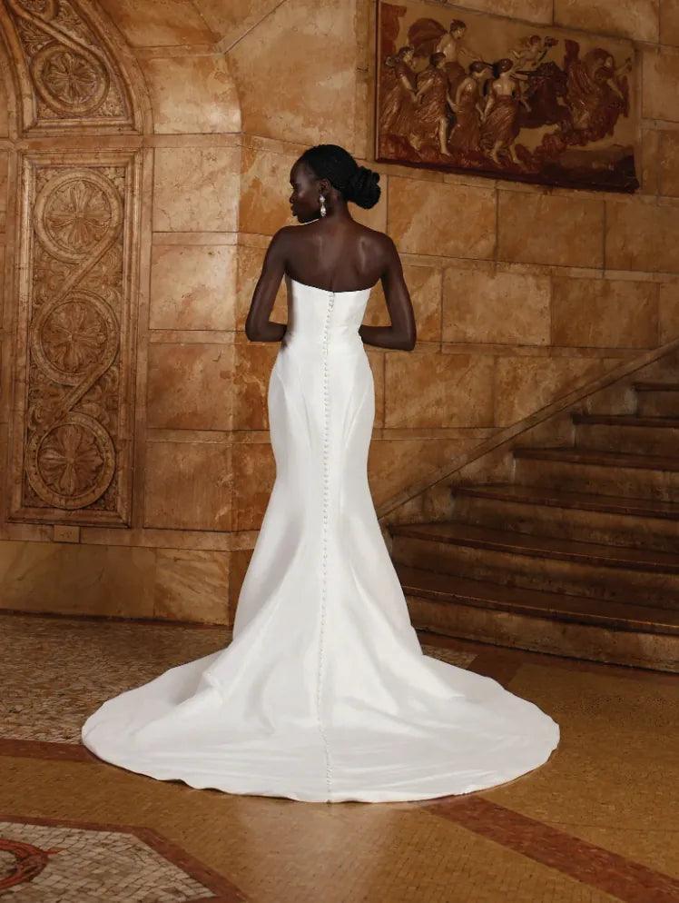 Woman in a white wedding dress standing in a room with decorative walls.