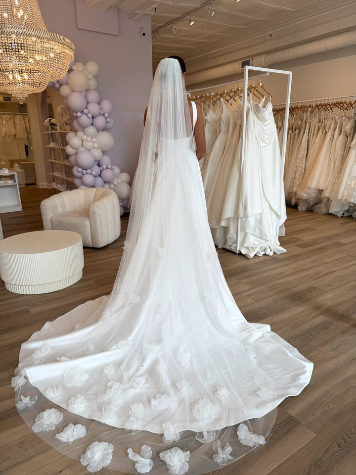 White wedding dress with floral details in a bridal shop setting