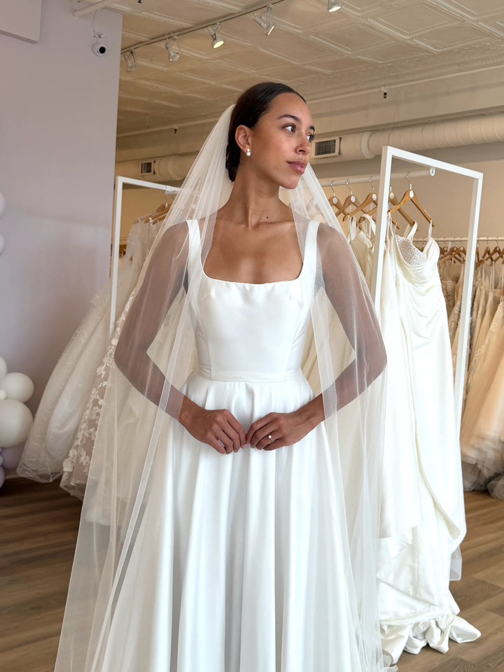 Woman wearing a white wedding dress with a veil in a bridal store.