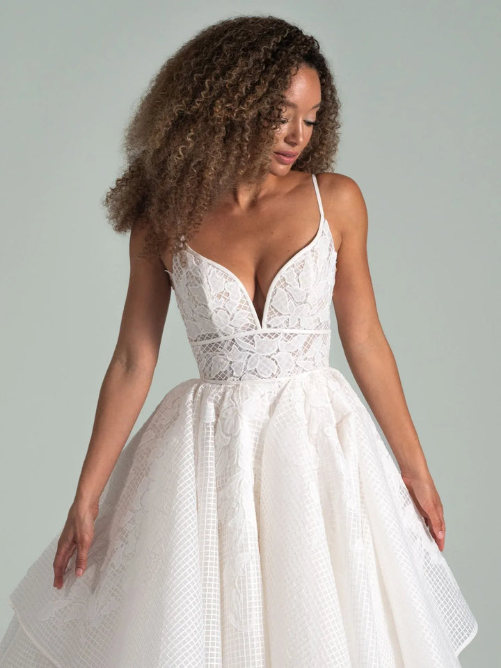 Woman wearing a white lace wedding dress against a plain background