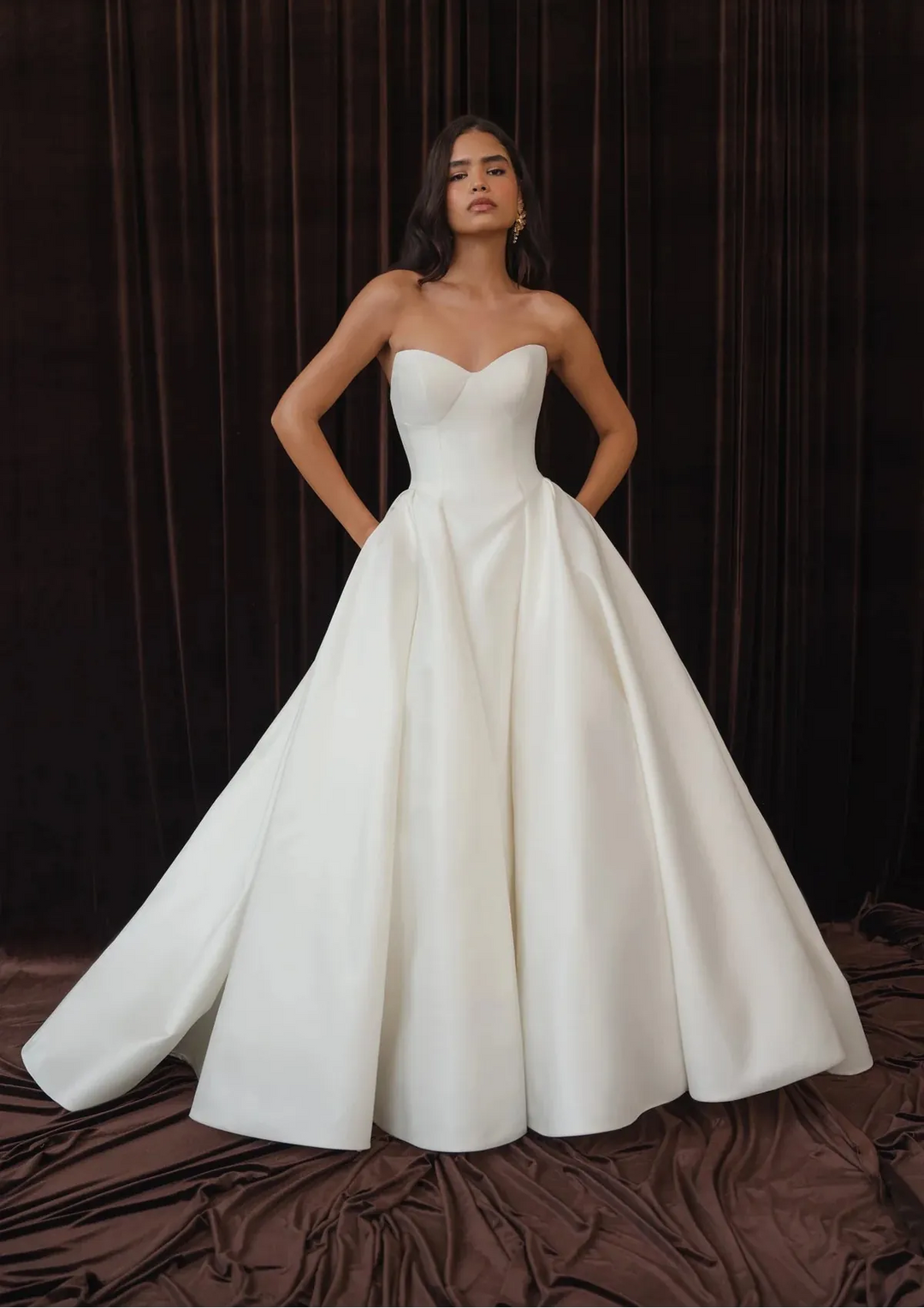 Woman wearing a white strapless gown against a dark background