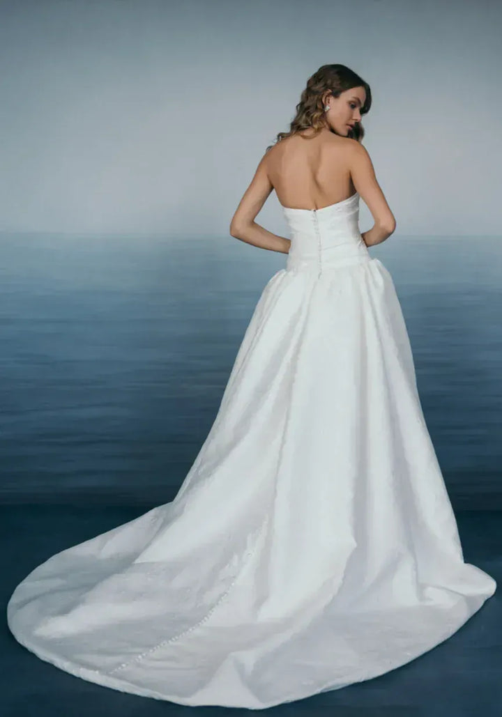 Woman in a white wedding dress standing against a gradient blue background