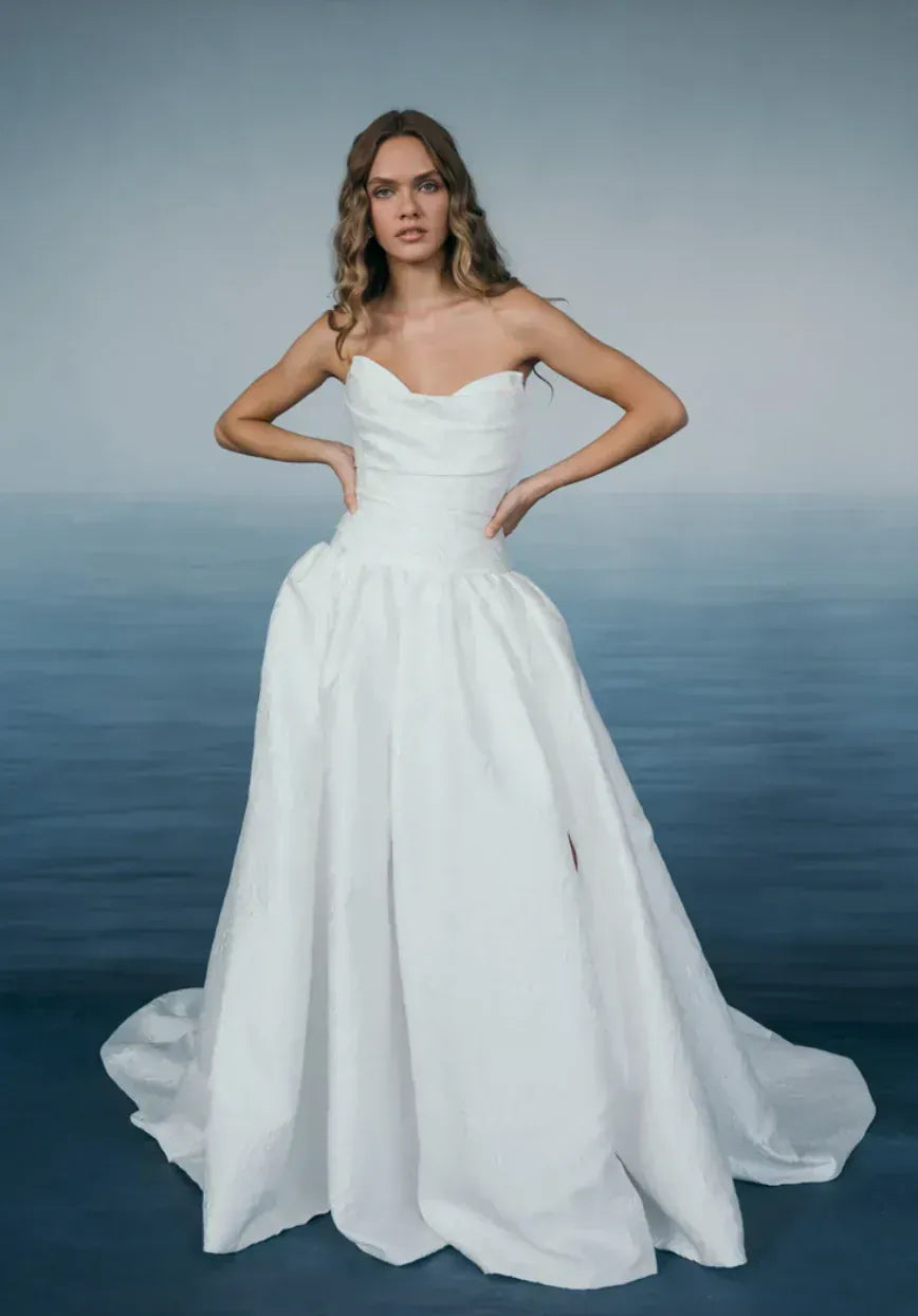 Woman in a white wedding dress standing against a blue gradient background
