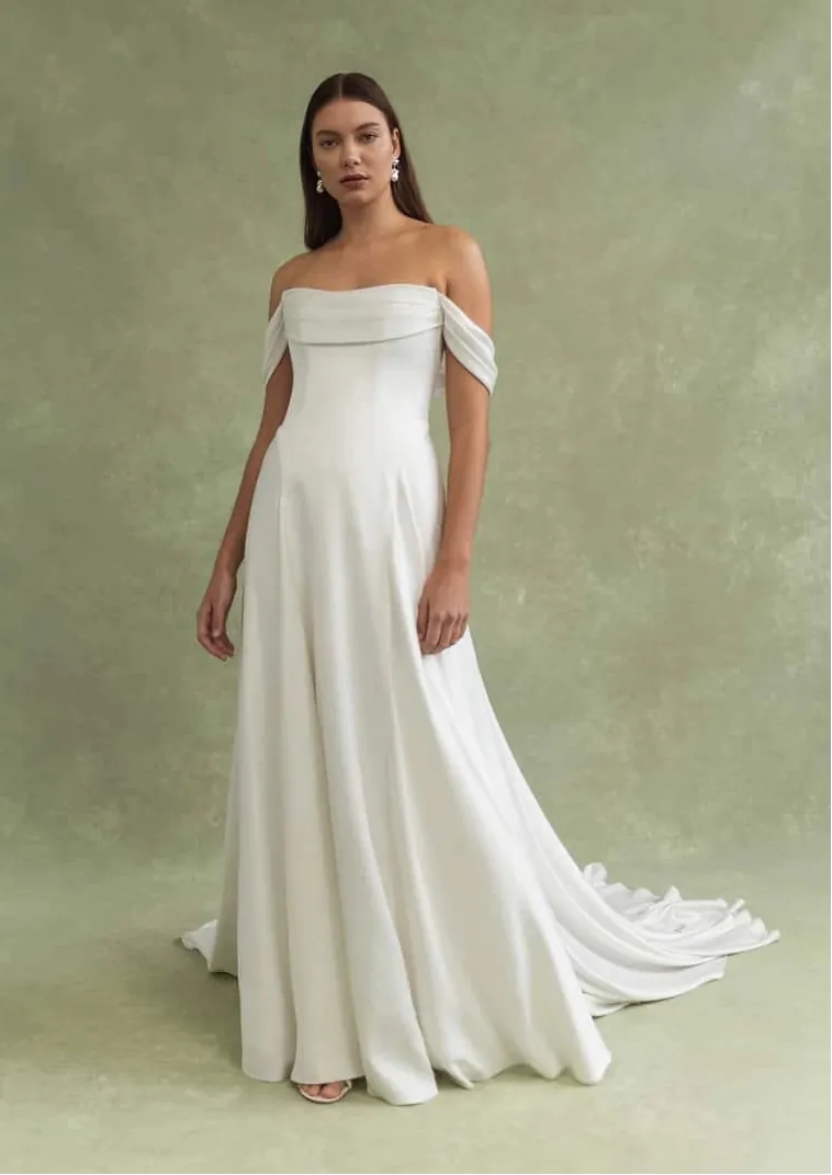 Woman wearing a white off-shoulder gown against a green background