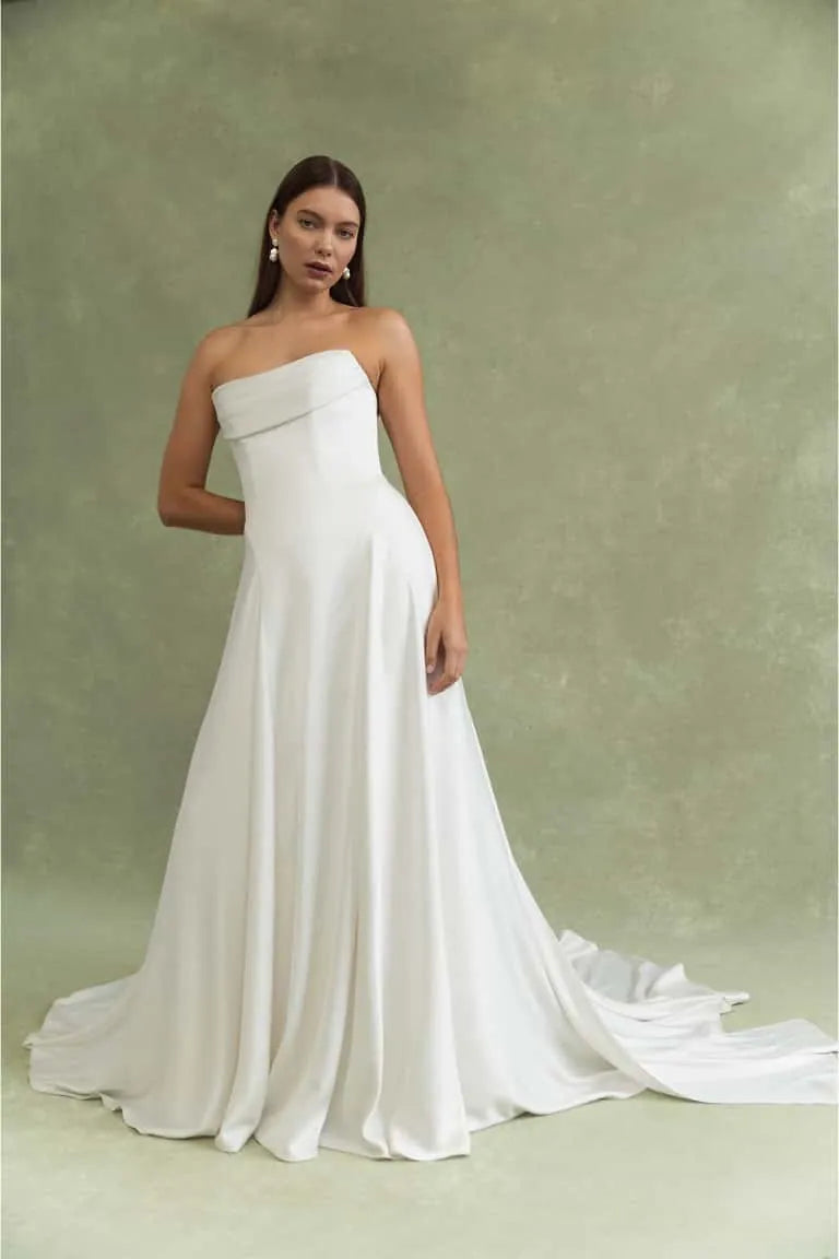 Woman wearing a strapless white wedding dress against a green background