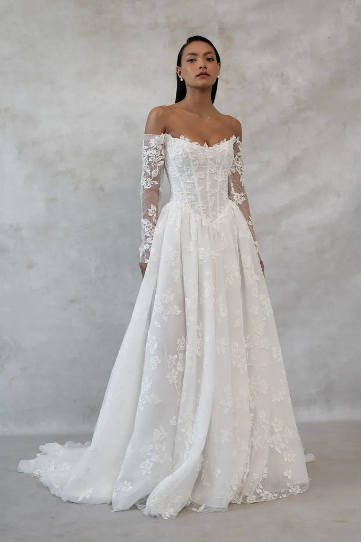 Woman wearing a white lace wedding dress against a plain background