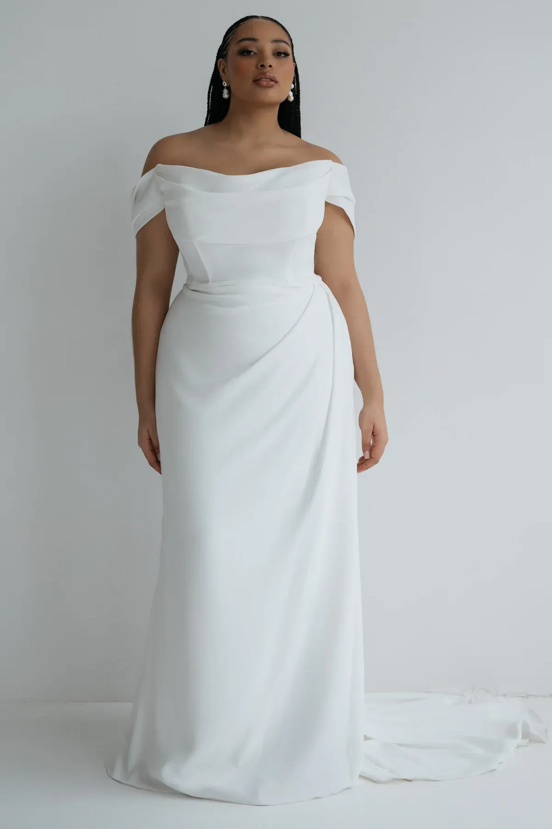 Woman wearing a white off-shoulder gown against a plain background
