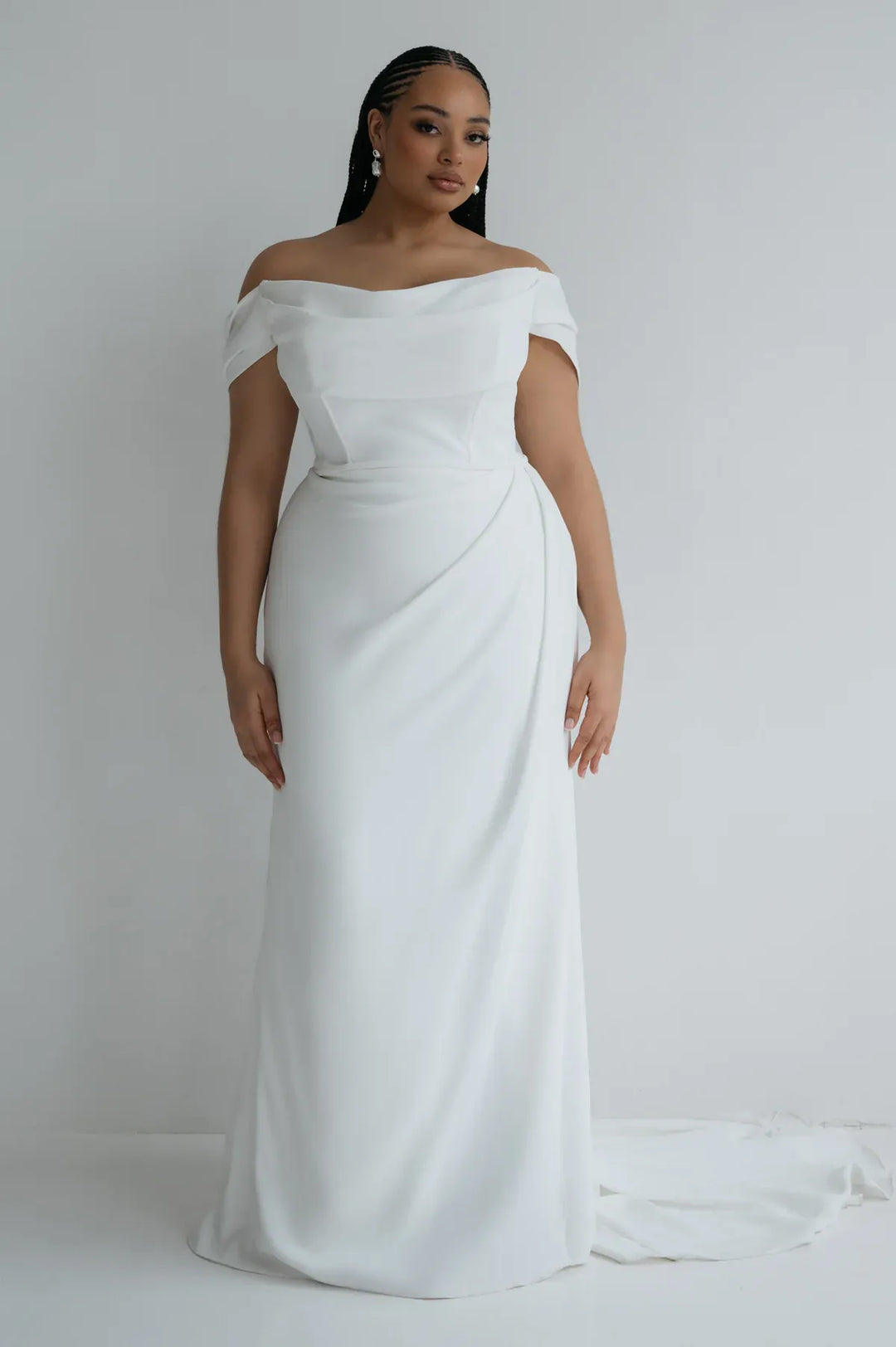 Woman wearing a white off-shoulder gown against a plain background