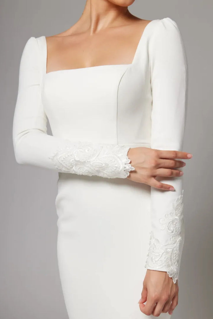 White long-sleeve dress with lace cuffs on a gray background